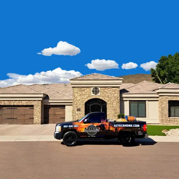 AZTECA company truck parked in front of a large home, bright blue sky