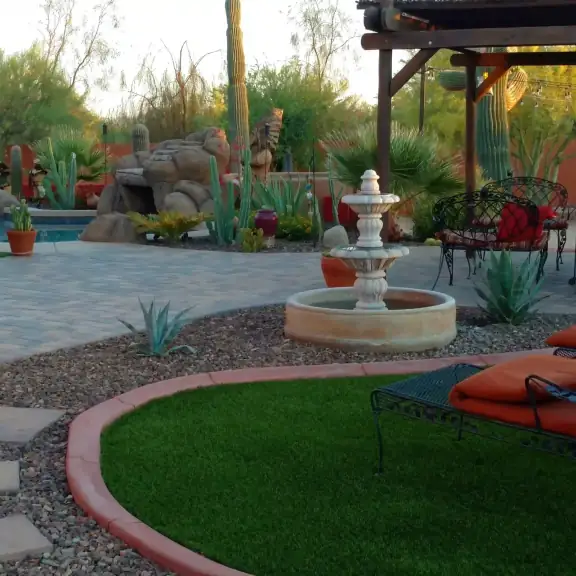 Desert backyard with fountain, pavers, turf and lounge chairs