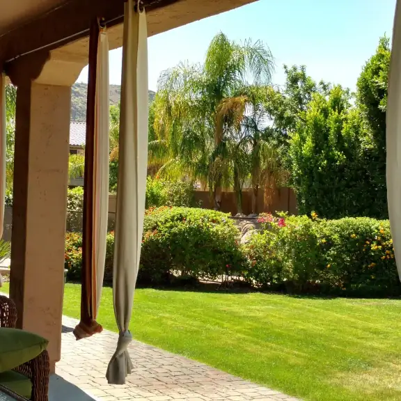 Shaded patio looking out on a green lawn and hedges