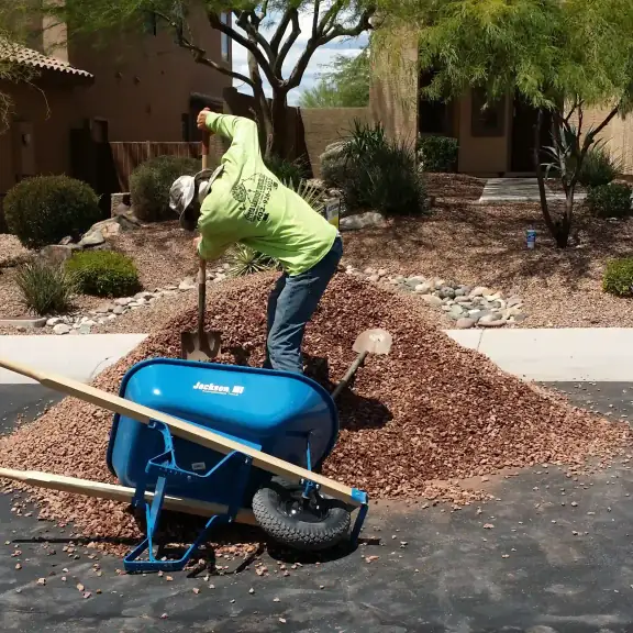 Worker spreading decorative rock with a wheelbarrow