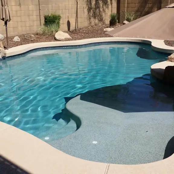 Freeform pool with umbrella and boulders